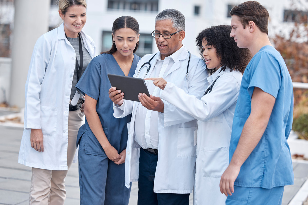 Team of doctors and medical staff reviewing pathology cases on a tablet
